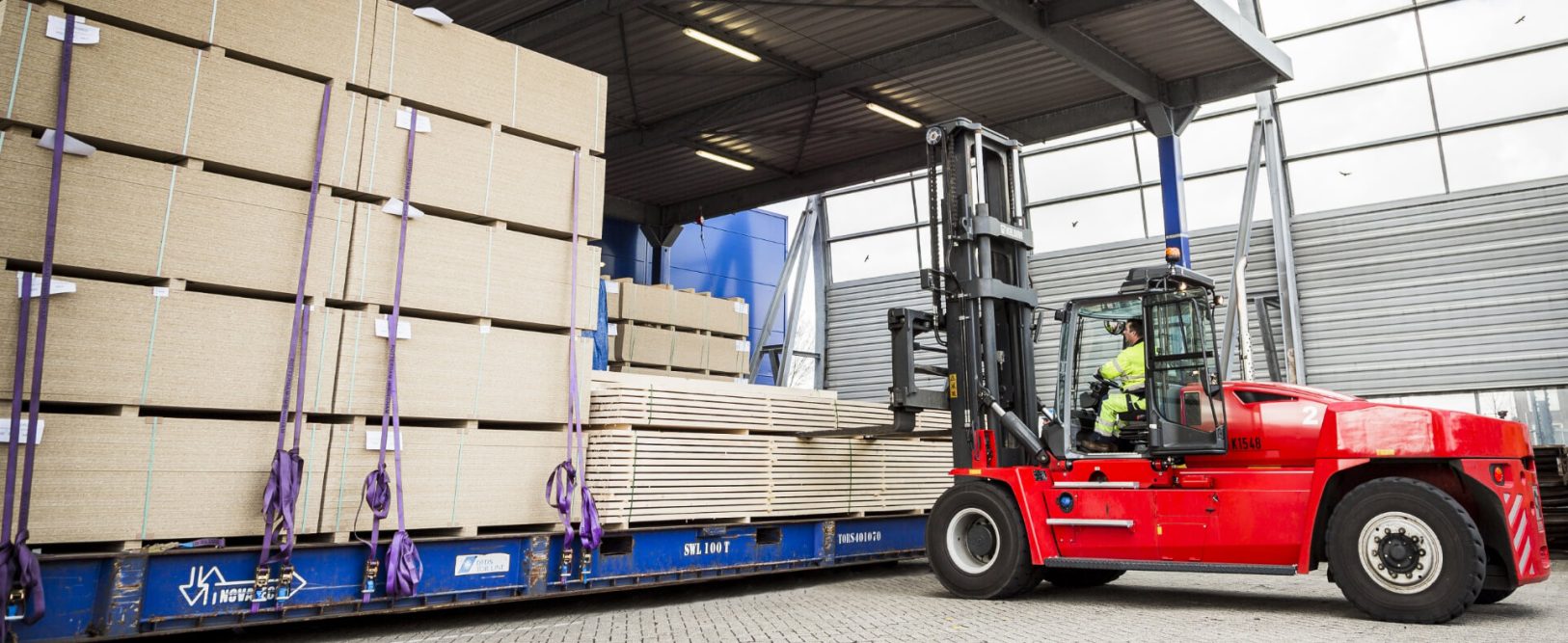 Heavy-Duty Forklift Rental Loading Lumber onto a Flatbed Trailer in an Industrial Yard